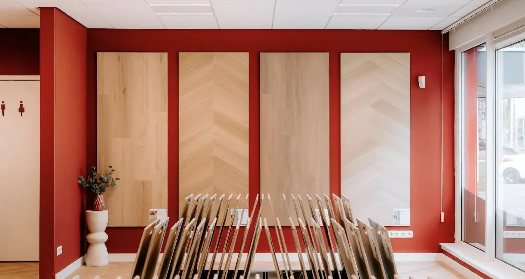 Wall panels and floor samples against the red showroom wall