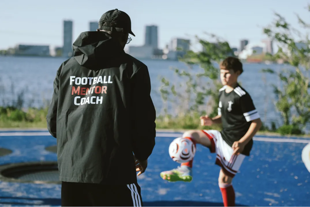 A Football Mentor Coach mentor training with a young player